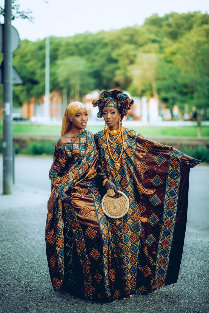 creative Two African women in vibrant traditional clothing, posing elegantly outdoors. Captures cultural heritage.